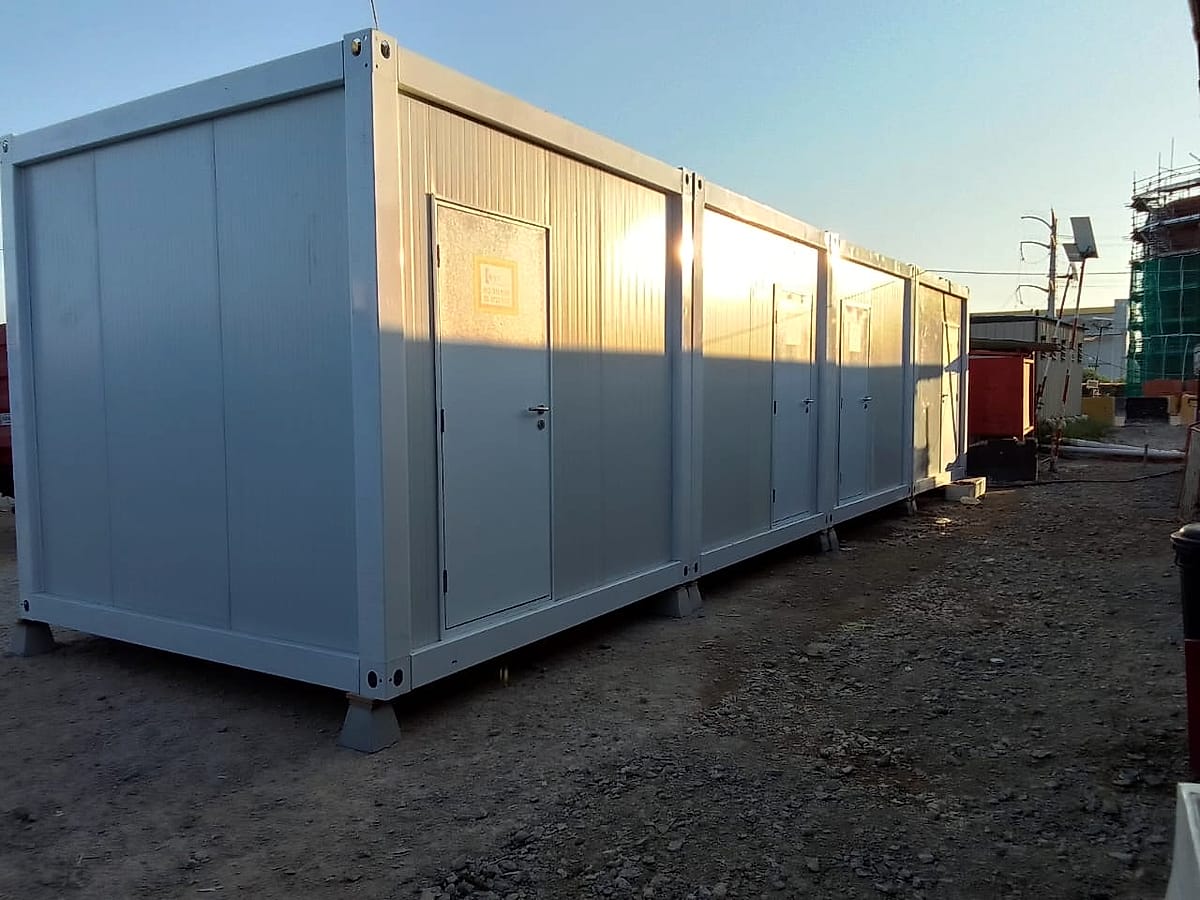 Row of four joined white container toilet cabins on a site at sunset