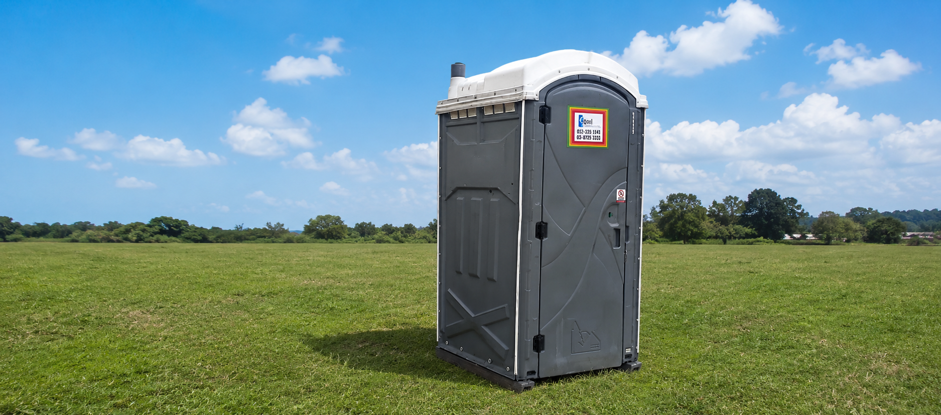 EQool portable toilet standing on a green grass field under a blue sky