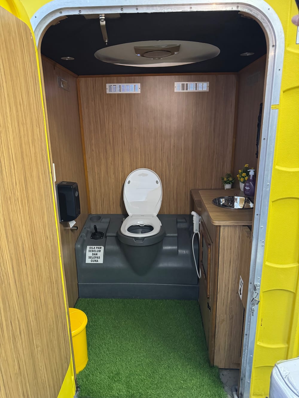 Inside the VIP unit: wood-panel walls, stainless basin, bidet spray and artificial grass floor
