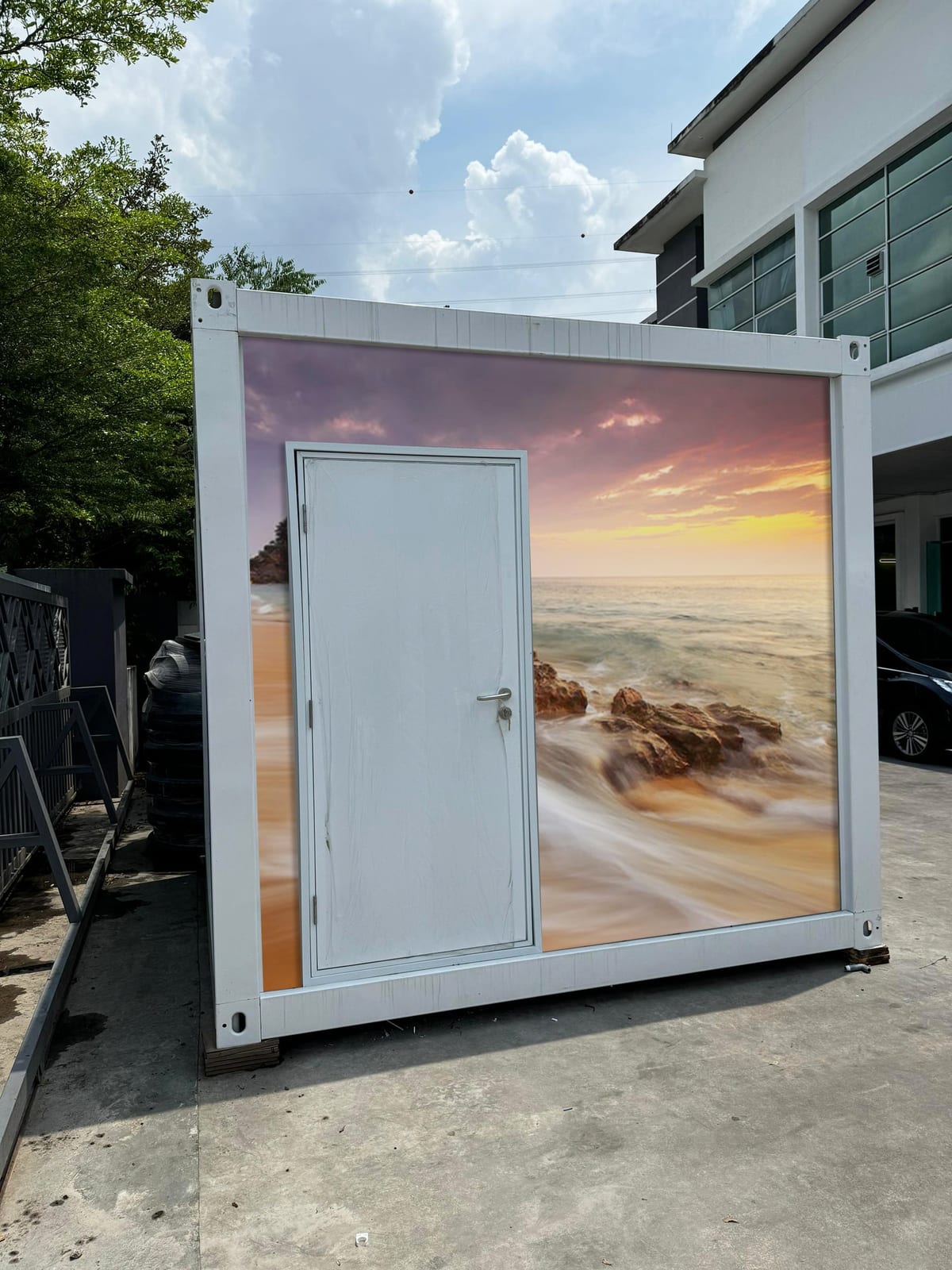 EQool event cabin toilet wrapped with a sunset beach and rocky shoreline mural