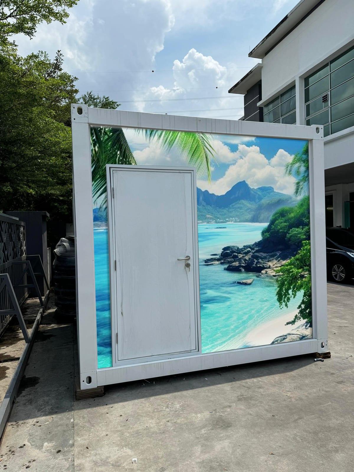 EQool event cabin toilet wrapped with a tropical turquoise bay and palm leaf mural