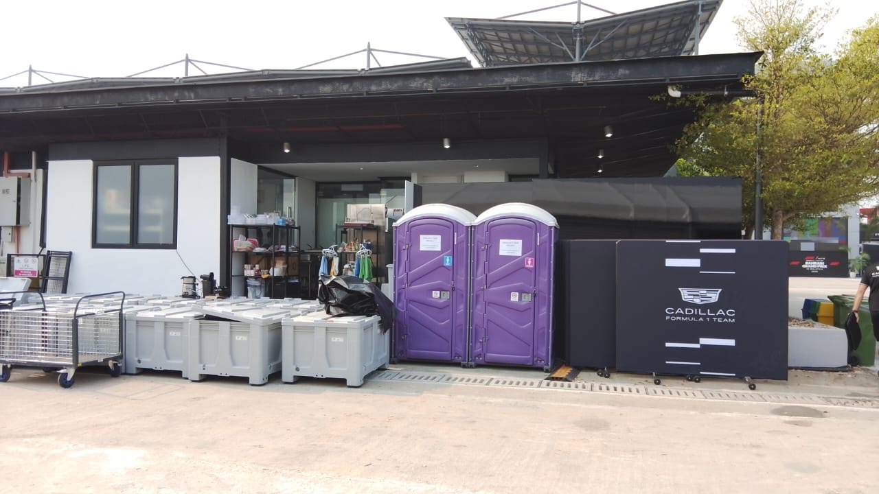 Two purple EQool portable toilets next to the Cadillac Formula 1 Team hospitality area
