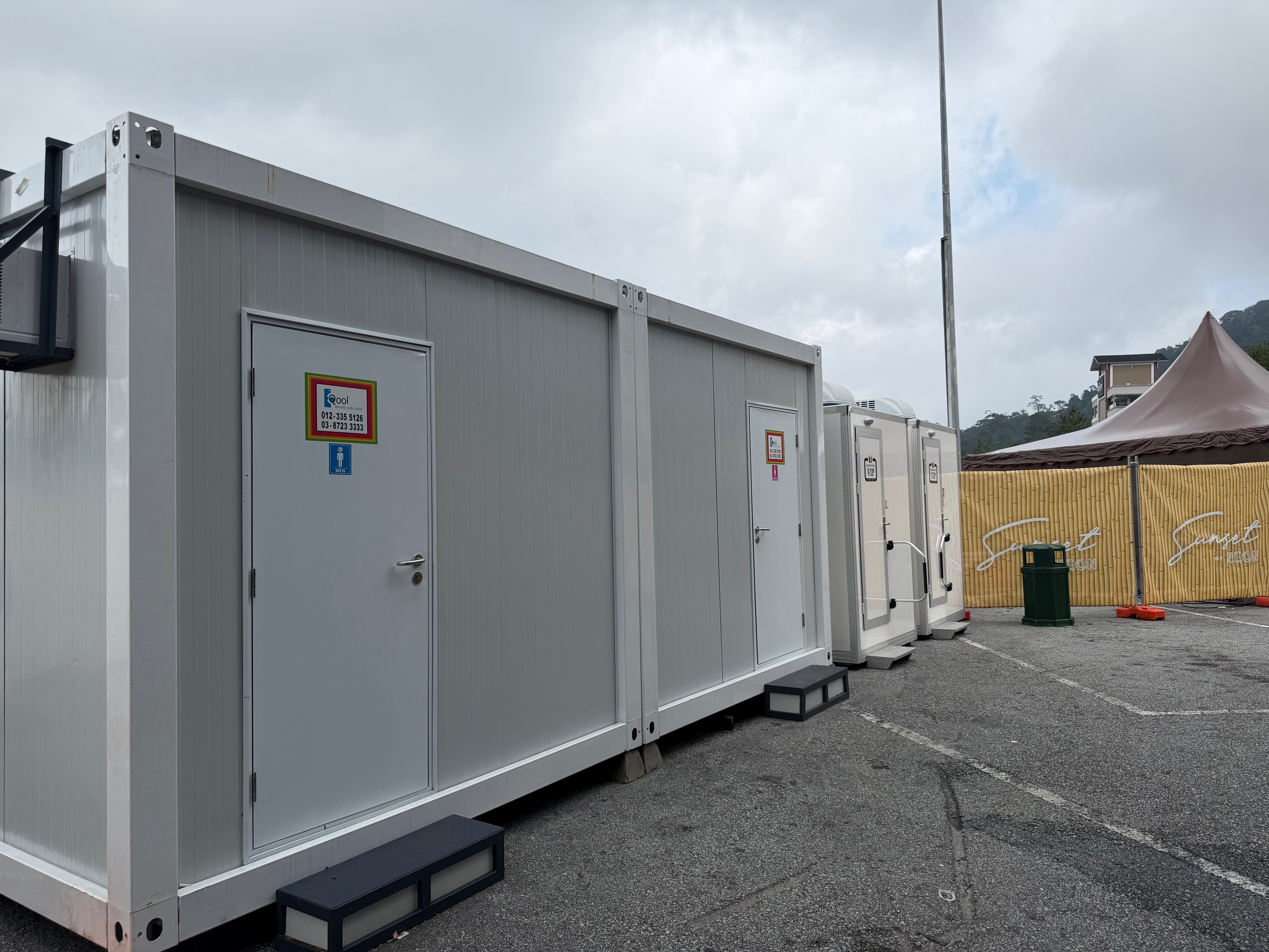 White EQool cabin toilets for men and women beside two VIP units and Sunset by NEON bamboo-pattern fencing