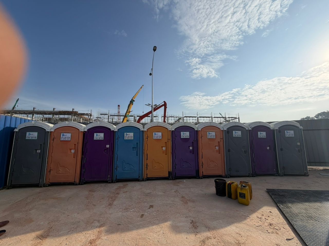 EQool colourful portable toilet units lined up at a large industrial construction site in Malaysia